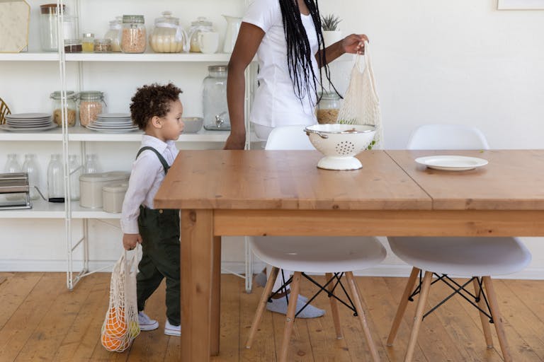 A mother and child carrying groceries in a stylish and organized dining room.
