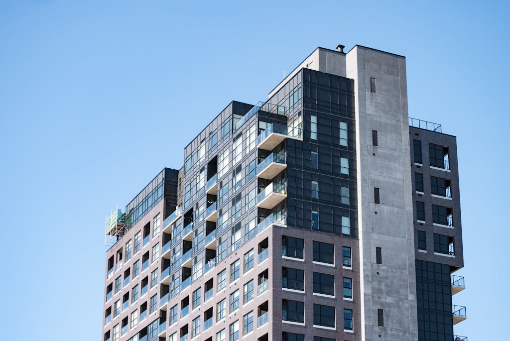 Contemporary high-rise apartment building with balconies against a blue sky.