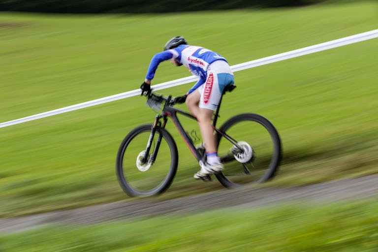 Cyclist racing downhill on a mountain bike at high speed outdoors.