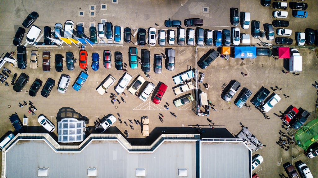 Drone shot showing cars and people in a parking lot in Rostock, Germany.
